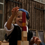 A child playing with the blocks from the Wooden Story 30 Rainbow Blocks set. The child is stacking the blocks on top of each other.