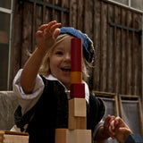 A child playing with the blocks from the Wooden Story 30 Rainbow Blocks set. The child is stacking the blocks on top of each other.