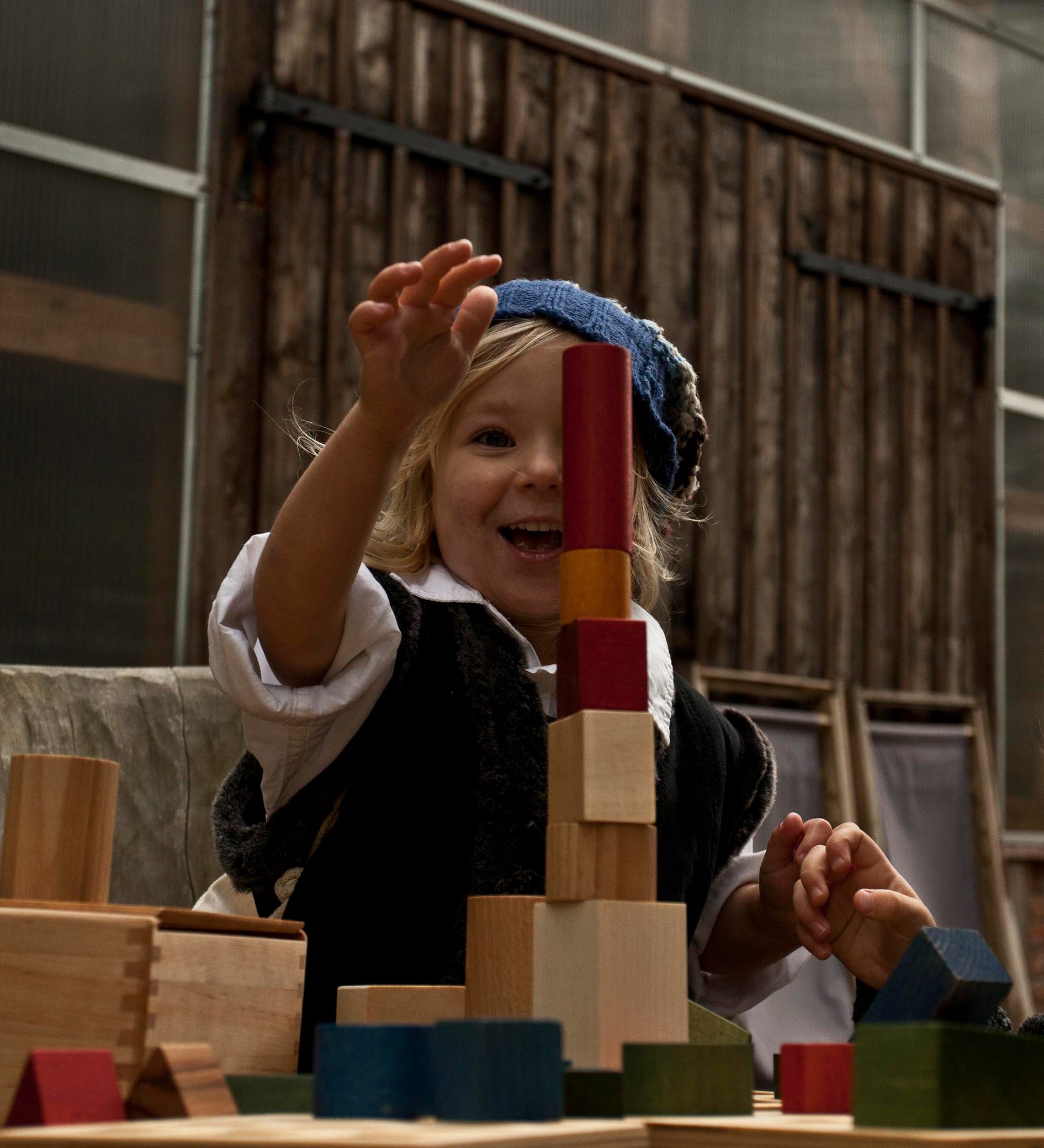 A child playing with Wooden Story Rainbow Blocks. The child is stacking the blocks on top of each other in a tower. 