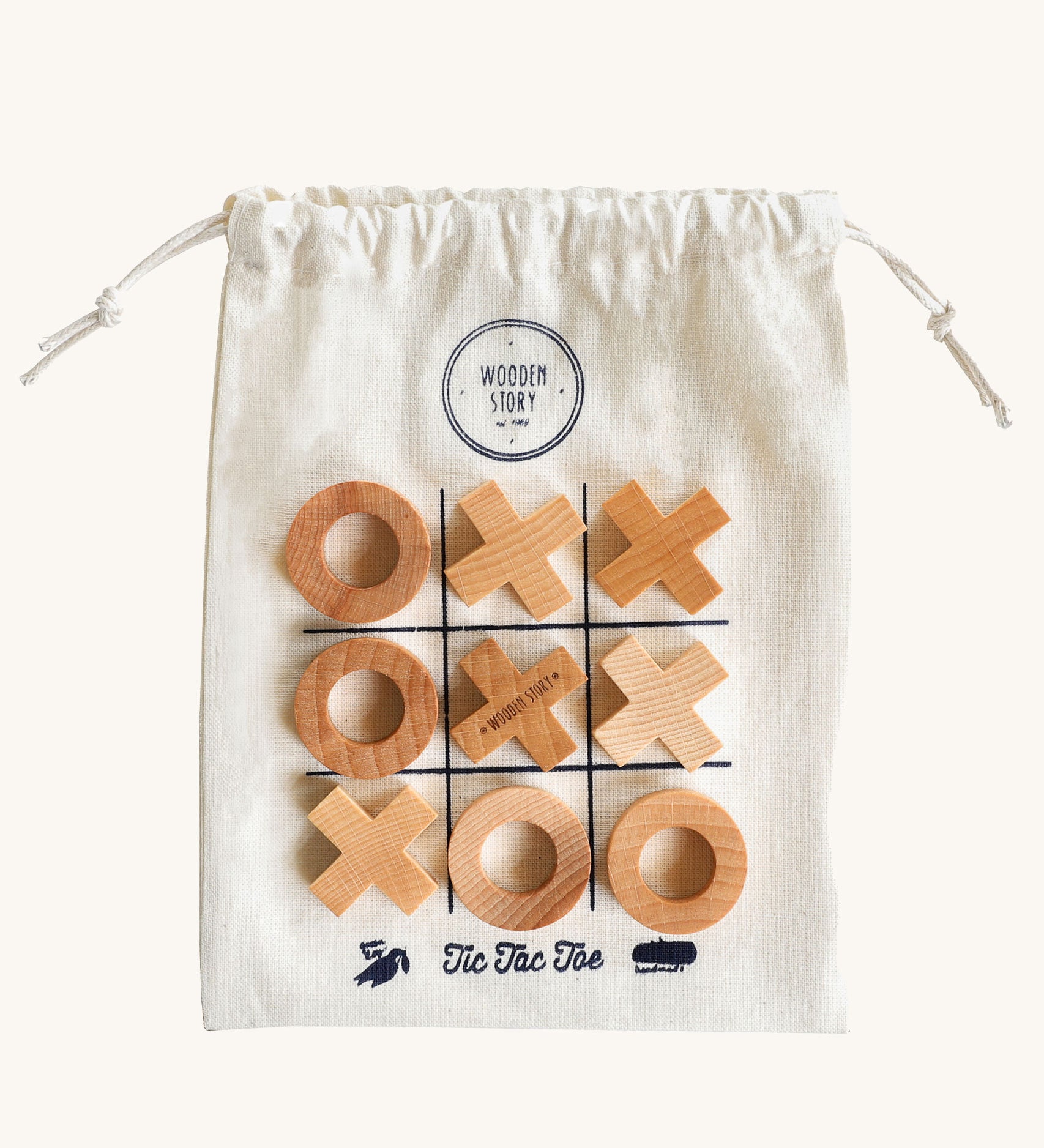 Wooden Story Tic Tac Toe game on a plain background. The wooden X and O pieces are placed on the drawstring bag which has the grid printed on it. 