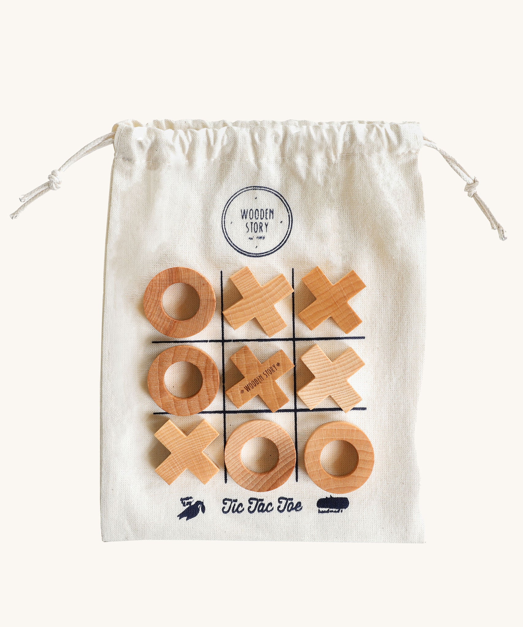 Wooden Story Tic Tac Toe game on a plain background. The wooden X and O pieces are placed on the drawstring bag which has the grid printed on it. 