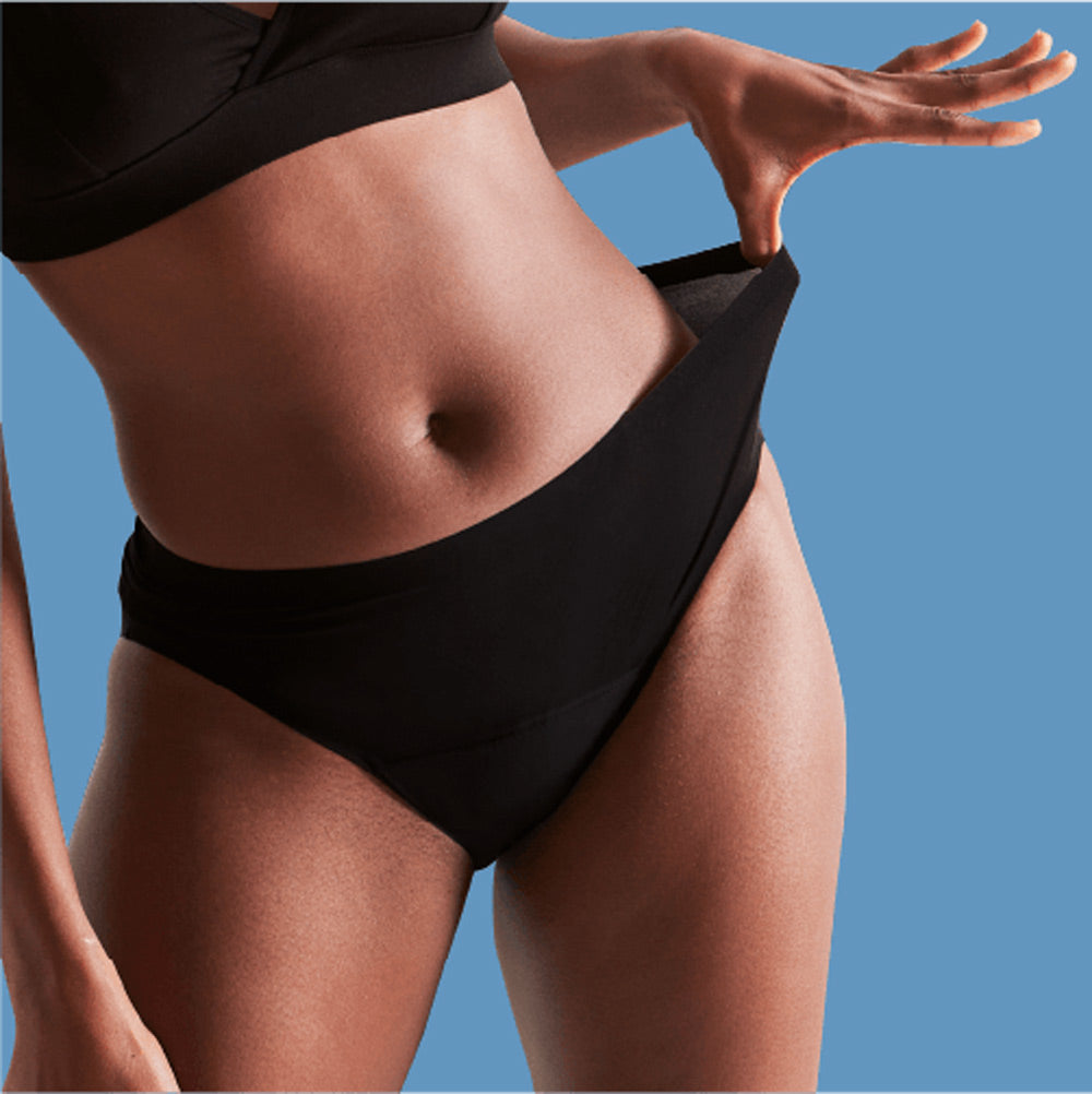 Close up of woman wearing the WUKA reusable performance seamless midi brief period pants on a blue background