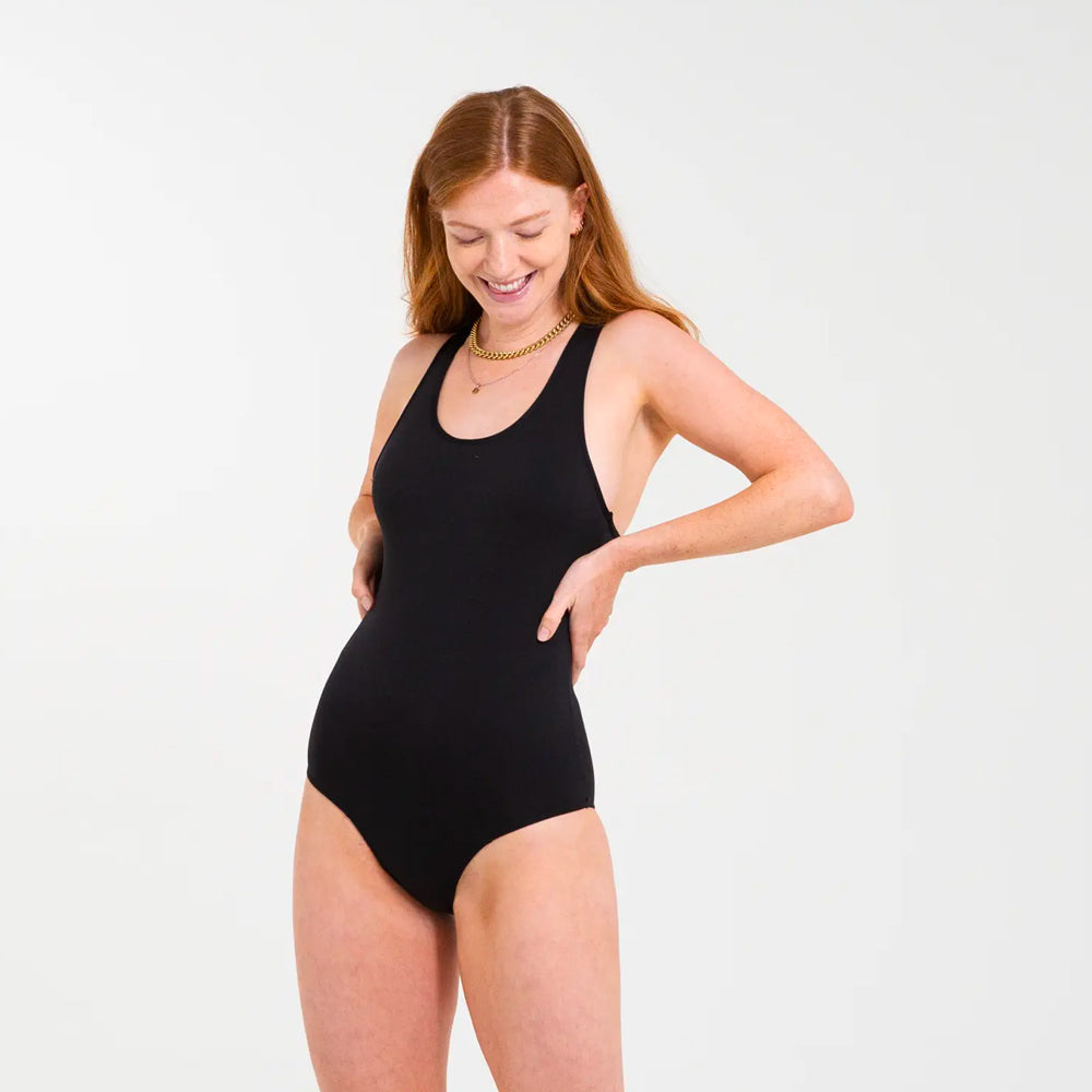 Woman stood on a grey background wearing the waterproof layered WUKA period swimsuit