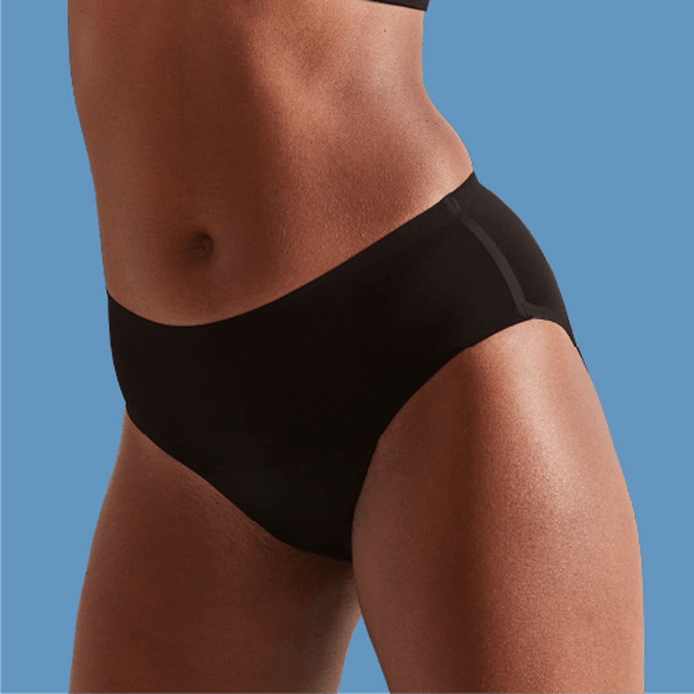 Close up of woman wearing the light flow WUKA seamless midi brief performance period pants on a blue background