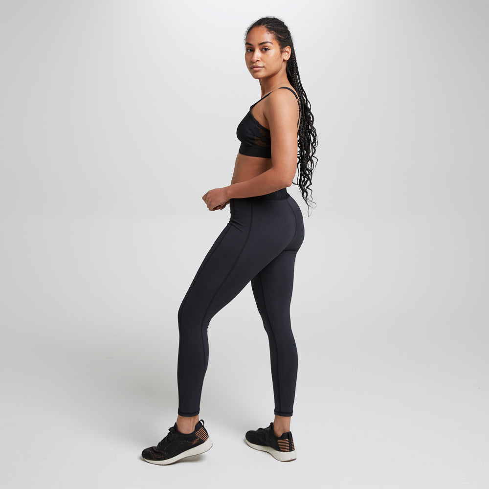 Woman stood on a grey background wearing the eco-friendly WUKA performance period leggings