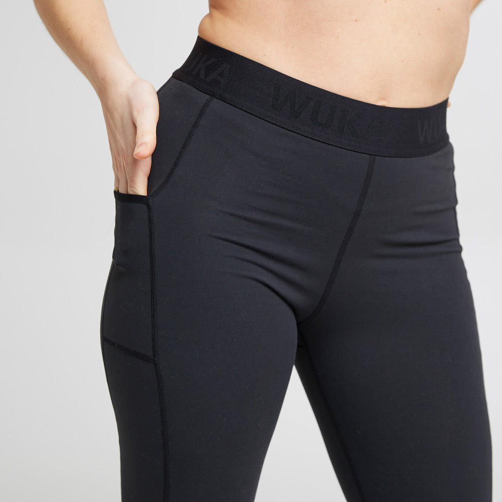 Close up of woman putting her hand in the pocket of the WUKA eco-friendly performance period leggings on a white background